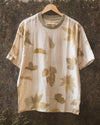 Botanical T-Shirt in natural white textured cotton hanging outdoors, eco printed with foraged leaves.
