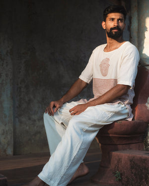 Model seated wearing an organic mulmul cotton kurta in rust